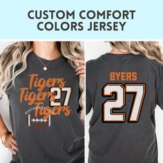 Show your team spirit with this custom Comfort Colors tshirt perfect for GAME DAY! Customize not only your color, but your school name, and player number. :)  HOW TO ORDER SHIRTS 1. REVIEW ALL PHOTOS for size and color options, as well as shop policy. 2. CHOOSE SHIRT SIZE from the drop-down menu. Notice the size guidance graphic if you want the trendy oversized look.  3. CHOOSE SHIRT COLOR from drop-down menu. 4. INSERT PERSONALIZATION 5. ADD TO CART (If ordering multiples, repeat steps 2-5) 6. CHECKOUT after carefully reviewing your cart. We welcome questions so please don't hesitate to send us a note.  PRODUCT MATERIAL DETAILS: Comfort Colors garments UNISEX and are made 100% with ring-spun cotton. The soft-washed, garment-dyed fabric brings extra coziness to your wardrobe while the rela Collegiate T-shirt With Custom Print For Game Day, Collegiate T-shirt With Name Print For Fans, Customizable Crew Neck T-shirt For Fan Gear, Customizable T-shirt For Football Season, Team Spirit T-shirt With Team Name For College, Custom Print Crew Neck T-shirt For Game Day, Varsity T-shirt With Team Name For College, Customizable Casual T-shirt For Cheerleading, Team-colored Crew Neck T-shirt For Cheerleading