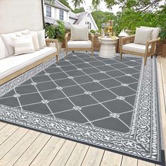 an outdoor area rug is shown with chairs and couches on the deck, in front of a house