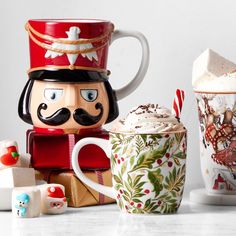 two mugs, one decorated like a nutcracker and the other as christmas decorations