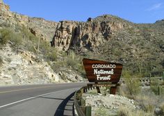 a road with a sign that says coronano national forest in front of some mountains