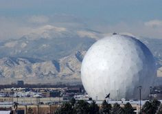 a large white ball sitting in the middle of a field with mountains in the background