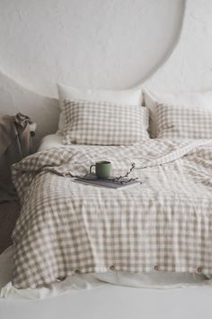 a coffee cup sitting on top of a bed next to pillows and blankets in a room