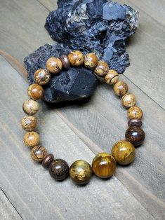 If warm earthy colors are your jam then this bracelet is for you. The backbone of this bracelet is 8mm Picture Jasper. The perfect Jasper that oozes earth energy. Up front there's three large 12mm Nellites flanked on each side by a 10mm Bronzite. Once again Nellite is the mineral vein where Pietersite and Tiger Eye collide. I apologize for repeating that description in this and other posts but it's just not a well known stone. The metal spacers are copper coated brass beads. They look like cute Brown Jasper Round Bead Bracelets, Brown Jasper Bracelets With Round Beads, Earthy Brown Beaded Bracelets With Gemstone Beads, Brown Jasper Bracelets With Natural Stones, Earthy Brown Bracelets With Gemstone Beads, Earthy Brown Jasper Beaded Bracelets, Earthy Brown Gemstone Beads Bracelets, Earth Energy, Jasper Bracelet