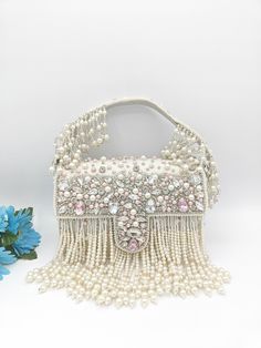 "Premium Quality Heavy Rhinestones Beaded Handmade  Wedding Purse The purse has beautiful beadwork. The purse is made of velvet and heavily beaded with rhinestones all over. The team of artisans has done a fantastic job. These bags are ideal for wedding functions, but you can also have them daily. These are ideal for parties, receptions, and gifts. These are small fancy bags designed for putting money, coins, and make-up touch-up kits.  The bag is heavy and one of a kind. It has a heavily beaded Embellished Pearl Evening Bag, Party Embellished Pearl Evening Bag, Formal Embellished Pearl Evening Bag, Pearl White Beaded Shoulder Bag For Party, Luxury Embellished Pearl Bag, White Evening Bag With Pearl Embroidery For Party, Pearl White Beaded Evening Bag For Party, Luxury Embellished Shoulder Bag For Reception, White Embellished Clutch Bag