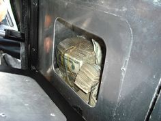 a bunch of money is in the back of a truck door that's open