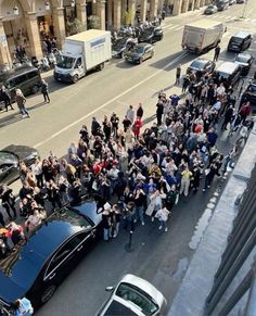 a group of people standing on the side of a road next to a black car