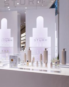 a display case filled with lots of different types of perfumes in front of a white wall