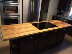 a kitchen with stainless steel appliances and wooden counter tops, along with an island in the middle