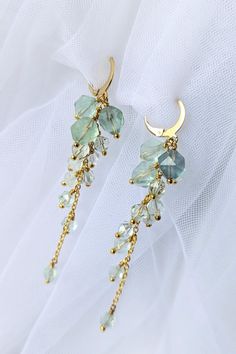 These exquisite earrings are adorned with a cluster of faceted fluorite gemstones, cascading like a delicate grapevine. Each earring features a unique arrangement of fluorite stones, ranging from bigger to smaller at the bottom. The gold plated chain adds a touch of elegance and complements the natural beauty of the fluorite. Material:  * Fluorite gemstones  * Gold-plated chain  * Hypoallergenic hook closure Measurements:  * Length: approx cm ( Care:  * Store in a cool, dry place away from direc Statement Earrings Gold, Sea Earrings, Gold Statement Earrings, Long Drop Earrings, Earrings Inspiration, Silver Plated Jewelry, Earrings Unique, Stunning Earrings, Cluster Earrings