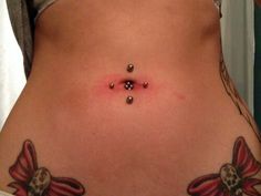 a woman's stomach with tattoos and piercings on it