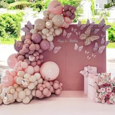 a pink and white birthday party with balloons on the top, butterflies on the back