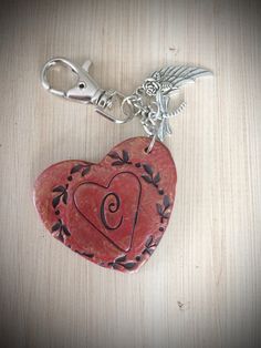 a red heart shaped keychain with an angel charm on it's side