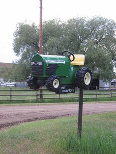 a tractor mounted on top of a wooden pole in front of a fenced area