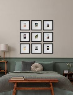 a bed sitting in a bedroom next to a wall with pictures hanging on the wall