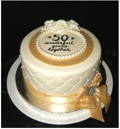 a 50th birthday cake decorated with gold ribbon and flowers