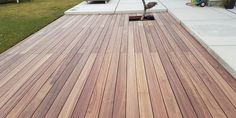 a wooden deck in front of a house next to a tree and grass covered yard