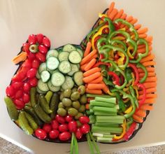 a heart shaped platter filled with veggies and cucumbers