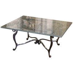 a glass table with wrought iron legs on an isolated white background for use as a coffee table