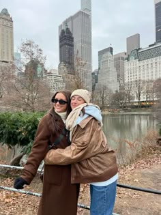 two women standing next to each other in front of a city