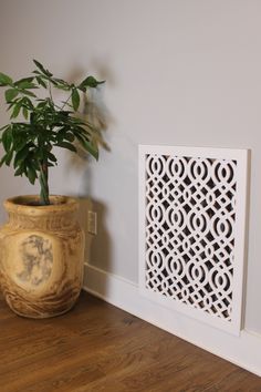 a potted plant sitting next to a wall with a decorative panel on it's side