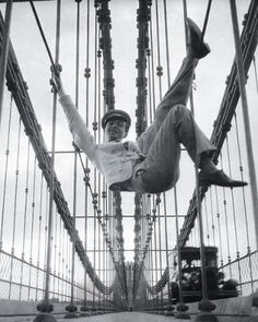 a man is hanging upside down on the bridge with his feet in the air and one leg up