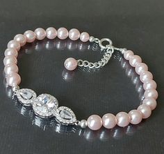 Wedding Blush Pink Light Pink Pearl CZ Silver Classic Bridal Bracelet. PLEASE READ ITEM DESCRIPTION and SHOP POLICIES before placing your order, and contact me with any questions! BRACELET is about 7.50 inches (19cm) long plus 1" extender chain. PINK PEARL JEWELRY: https://www.etsy.com/shop/LanaChayka?ref=seller-platform-mcnav&search_query=pink+pearls BRIDAL EARRINGS SECTION: https://www.etsy.com/shop/LanaChayka?ref=seller-platform-mcnav§ion_id=11638940 BRIDAL JEWELRY SETS SECTION: https://www.etsy.com/shop/LanaChayka?ref=seller-platform-mcnav§ion_id=25839214 BRIDAL NECKLACES SECTION: https://www.etsy.com/shop/LanaChayka?ref=seller-platform-mcnav§ion_id=11638944 Handmade bracelet, is made with Light Pink Rosaline Blush Pink color premium quality European round crystal pearls, Rhodium Plate Elegant Crystal Bracelet For Wedding, Elegant Round Crystal Bracelet For Wedding, Pink Pearl Bracelet For Wedding, Crystal Bracelet With Round Beads For Wedding, Adjustable Pink Crystal Bracelet For Wedding, Adjustable Silver Bridal Accessories For Bridal Shower, Adjustable Round Pearl Bracelet For Wedding, Pink Beaded Bangle Bracelets For Wedding, Adjustable Round Crystal Bracelet For Wedding