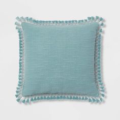 a light blue pillow with tassels on the sides and a white back ground