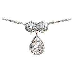 Incredible vintage diamond necklace bursting with Old World charm. This gorgeous piece boasts a simple yet elegant design, elevated by the intricate filigree detailing that really enhance the stunning Old European cut diamonds. This necklace is a true treasure. This beautiful drop necklace features 2 Old European cut natural diamonds (F-G in color, I1 in clarity) 6 prong set and arranged in hexagon shaped settings with delicate filigree borders. Dangling from the 2 stones is hinged teardrop shaped filigree drop featuring a single .85 carat Old European cut diamond (I / SI1) also surrounded by a hexagon setting. The 14 karat white gold setting really enhances the white brilliance of the stones, making this piece truly sparkle. The delicate chain is also made of 14 karat white gold and measu Vintage White Gold Necklace With Diamond Accents, Antique White Gold Necklace With Intricate Design, Classic Diamond Filigree Necklaces, Heirloom White Gold Necklace With Single Cut Diamonds, Antique White Gold Necklace With Single Cut Diamonds, Classic Diamond Filigree Necklace, Classic Diamond Necklace With Filigree Design, Classic Diamond Necklace With Filigree, White Gold Diamond Pendant Necklace With Intricate Design