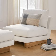 a white couch with two pillows and a coffee cup on the floor next to it