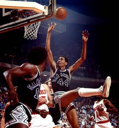 an image of a basketball game going on with the ball in the air and one player trying to block it