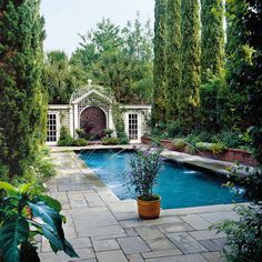 an outdoor swimming pool surrounded by greenery and stone pavers walkways with potted plants on either side