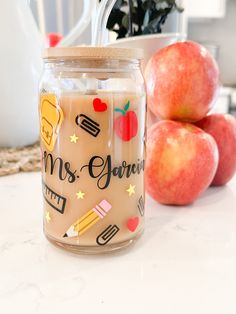 a glass jar filled with liquid sitting on top of a counter next to some apples