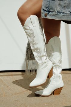 a woman wearing white cowboy boots and jeans