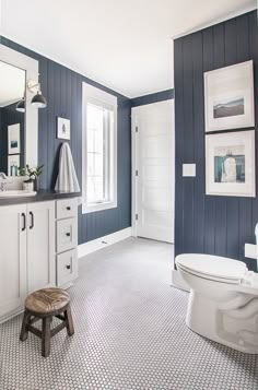 a white toilet sitting in a bathroom next to a sink under a mirror and a window