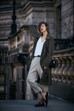 a woman is standing on the sidewalk in front of an old building and posing for a photo