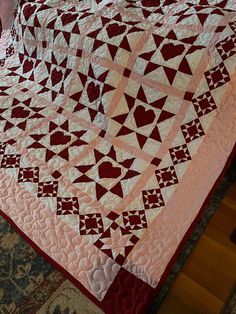 a pink and red quilt on top of a bed