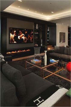 a living room with black furniture and a flat screen tv mounted on the wall next to a fire place