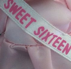 a pink shirt with the word sweet sixteen printed on it's collar and side