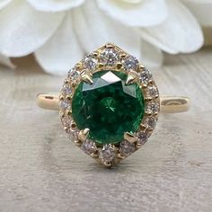 "The ring pictured is lab created emerald and moissanite #6410 This ring can be made with many different stone colors Message us for pricing on different color/type stones Emerald is the birthstone of May -Approximate total carat weight: 1.46 ctw diamond equivalent -Center Stone Size: 7mm - approx. 1.20ct diamond equivalent -Center Stone Shape: round - extra brilliant -Gem Type: lab created emerald -Stone Clarity: VS2 -Stone Color: lively medium green, eye-clean -Moh's Scale: 8.5 hardness -Accen Luxury Emerald Ring With Round Stone, Moissanite Emerald Ring For Anniversary, Green Diamond Ring With Halo Design, Green 14k Gold Halo Ring As A Gift, Green Halo Setting Jewelry For Anniversary, Green Jewelry With Halo Setting For Anniversary, Emerald Ring With Halo For May Birthstone, Halo Emerald Jewelry With Round Cut, Emerald Halo Jewelry With Round Cut