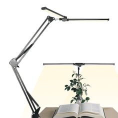 an open book sitting on top of a table next to a lamp and a plant