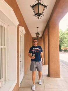 a man walking down a sidewalk holding a drink