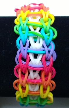 a stack of colorful bracelets sitting on top of each other in front of a black surface