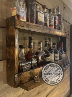 a wooden shelf filled with bottles of liquor on top of a wall next to a sign