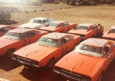 a group of orange muscle cars sitting in a parking lot