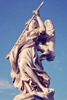 an angel statue holding a cross on top of a building