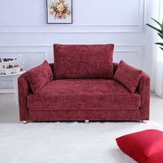 a red couch sitting on top of a white rug