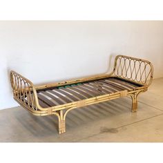 a bamboo bed frame sitting on top of a cement floor next to a white wall