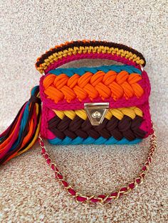 a multicolored purse sitting on top of a table next to a chain strap