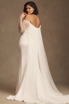 a woman in a white wedding dress posing for the camera with her back to the camera