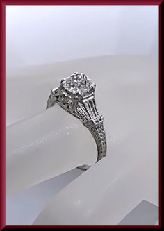 a diamond ring sitting on top of a white surface with a red frame around it